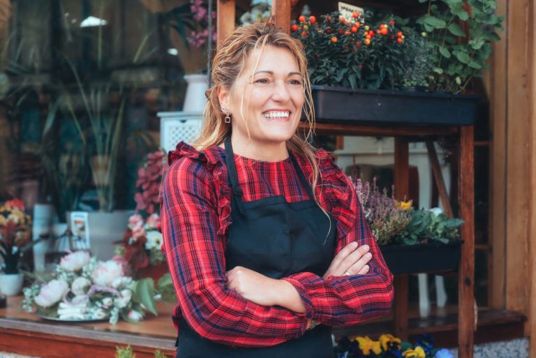 Small biz owner smiling at laptop with passive biz income 2025 ideas.